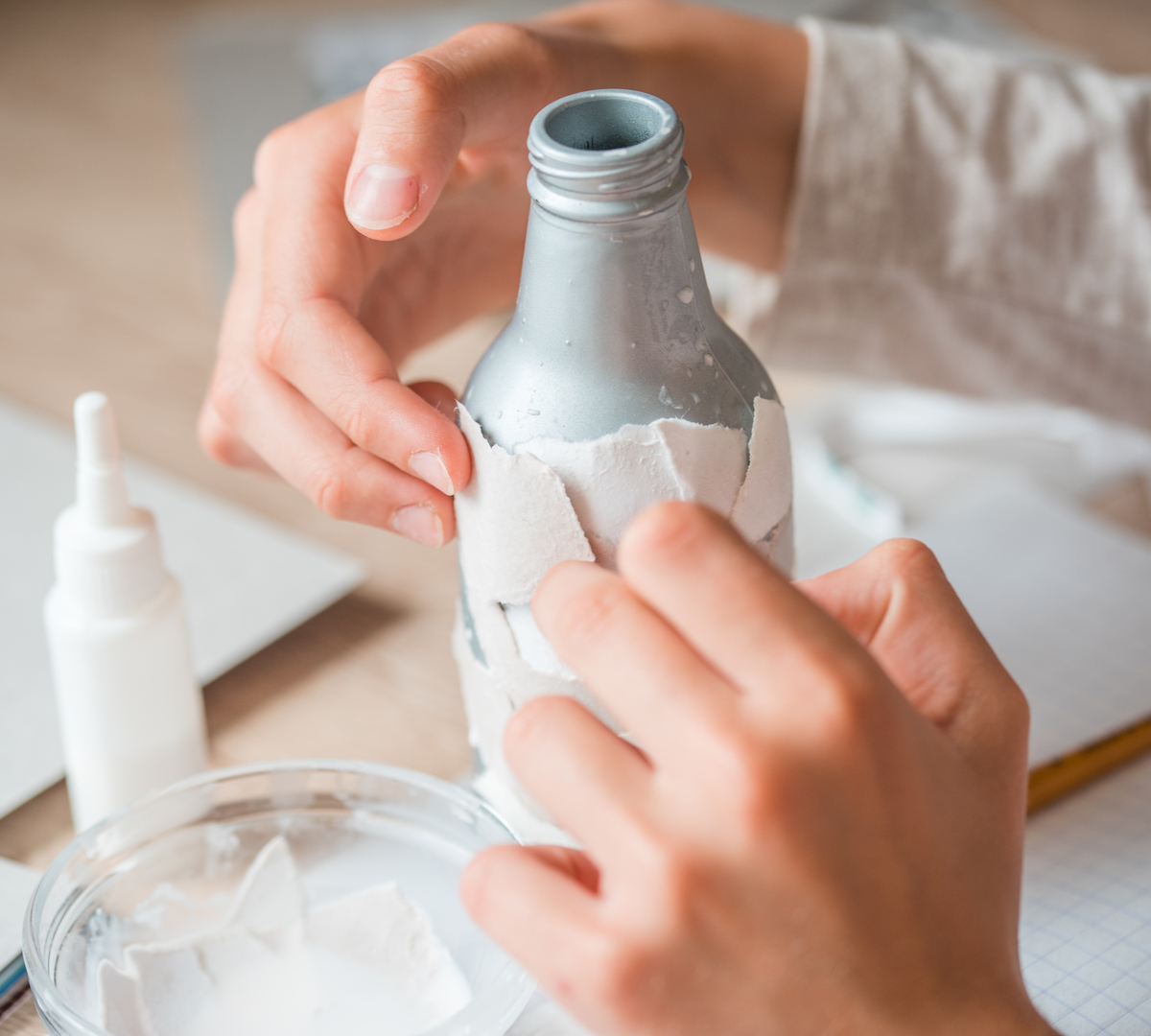 secondary use of paper debris. children's handmade from papier mache. The baby's hands are glued to pieces of paper on the bottle.